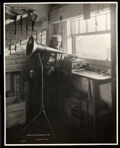 彼の研究室で蓄音機の隣に立っているトーマスエジソン、1920年（銀ゼラチンプリント） 作： Byron Company